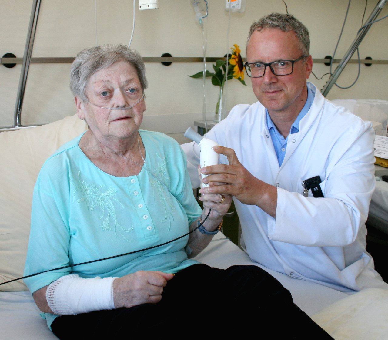 Professor Klaus Bumm, der Chefarzt der HNO-Klinik erklärt Patientin Rosemarie Quack die Selbsttherapie mit dem Zalviso-Applikator.